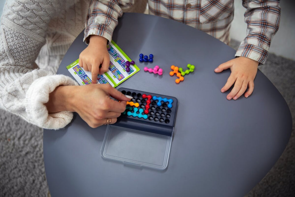 Mother and child playing with a colorful dot matching game on a board.