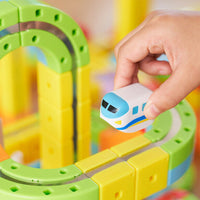 Close up on a hand placing a little train on the 3D Infinity Track. 