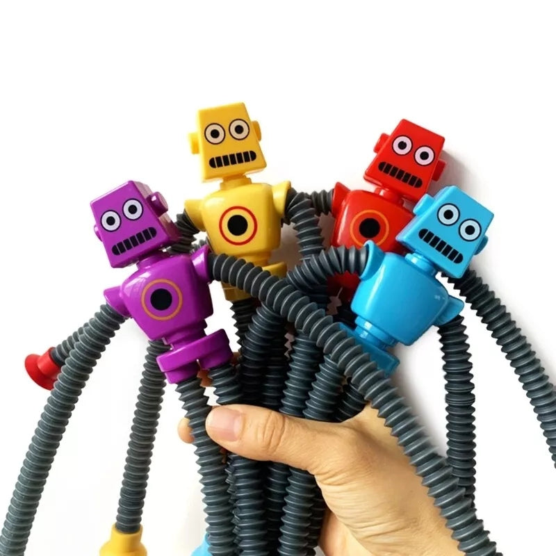 Hand holding a bundle of colorful robot toys with flexible, accordion-style arms and legs, featuring expressive faces and bright colors like purple, yellow, red, and blue.
