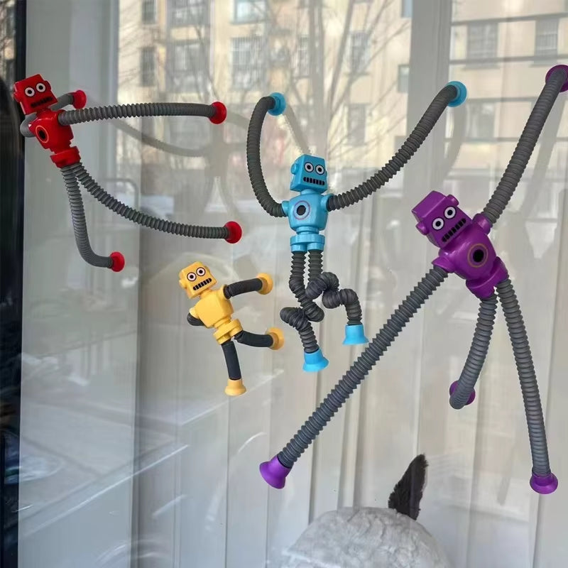 FlexiBots attached to a window via suction cups on their accordion-style arms and legs.
