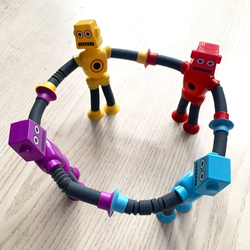Four colorful robot toys with bendable, accordion-style limbs connected in a circle, standing on a light wooden surface.