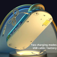 Bottom view of the Highway Star toy steering wheel game, showing two charging modes: USB cable and battery. The image highlights the battery compartment and USB charging port, emphasizing flexible power options. The toy features suction cups for secure attachment to surfaces. 