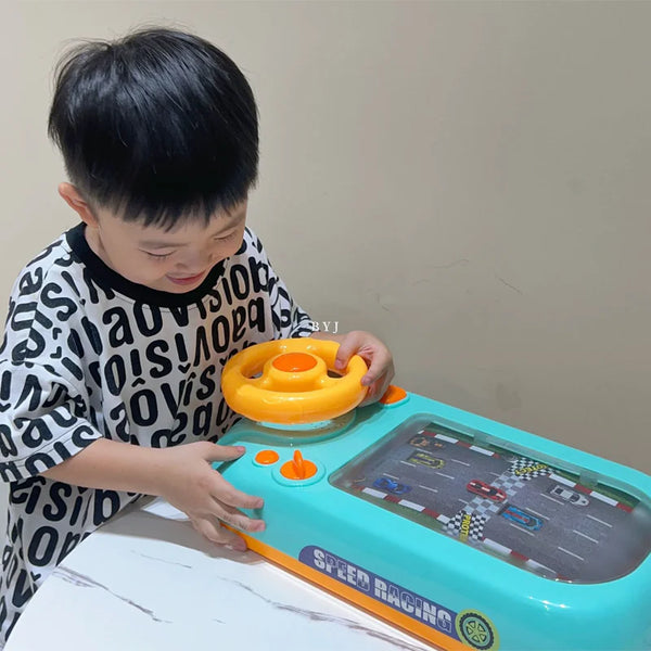 Young child playing with a Highway Hero toy steering wheel game. The interactive toy features a bright yellow steering wheel and a racing track display, providing a fun driving simulation experience. The child is smiling and engaged in play.