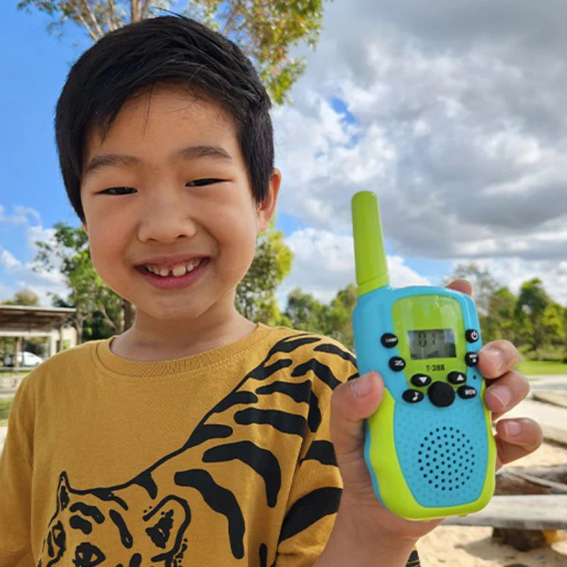 Child holding a walkie talkie and smiling.