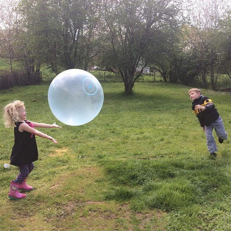 Brother and sister playing with a blue bouncy wobble ball in the backyard.