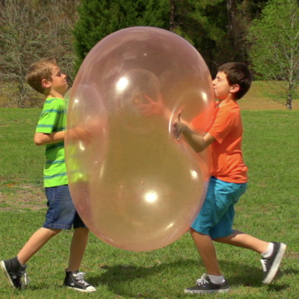 Two boys in the park playing with a Mega WobbleBall. 
